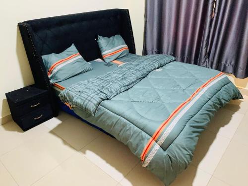 Bett mit blauer Bettdecke und Kissen in der Unterkunft Exquisite Apartments- 1Bedroom Kigali in Kigali