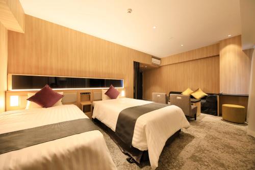 a hotel room with two beds and a desk at QuintessaHotel FukuokaTenjin Comic&Books in Fukuoka