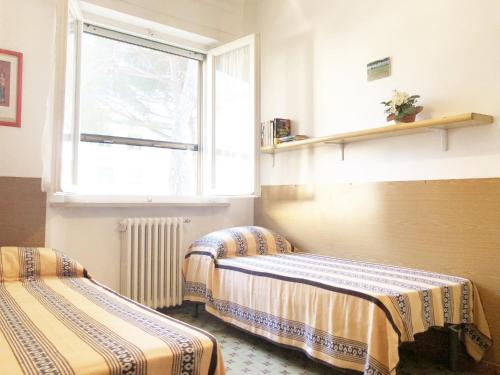 2 Betten in einem Zimmer mit Fenster in der Unterkunft Appartamento ALICE a Marina di Cecina in Marina di Cecina