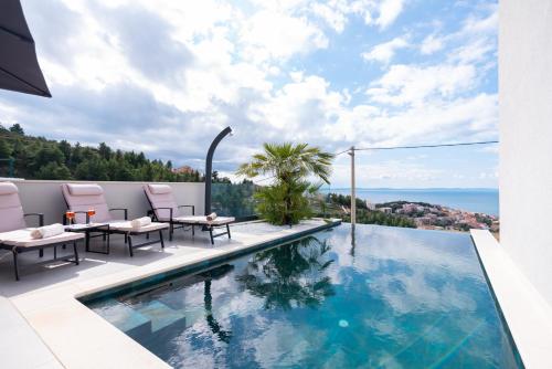 einen Pool mit zwei Tischen und Stühlen und das Meer in der Unterkunft Astonishing villa Blue Horizon w heated pool in Podstrana