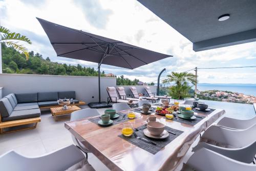 eine Terrasse mit Tisch und Stühlen und einem Sonnenschirm in der Unterkunft Astonishing villa Blue Horizon w heated pool in Podstrana