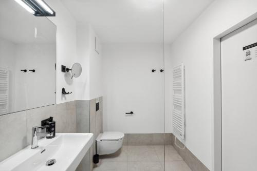 a white bathroom with a toilet and a sink at Limehome Salzburg Sterneckstr in Salzburg