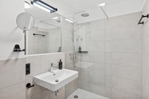 a white bathroom with a sink and a mirror at Limehome Salzburg Sterneckstr in Salzburg