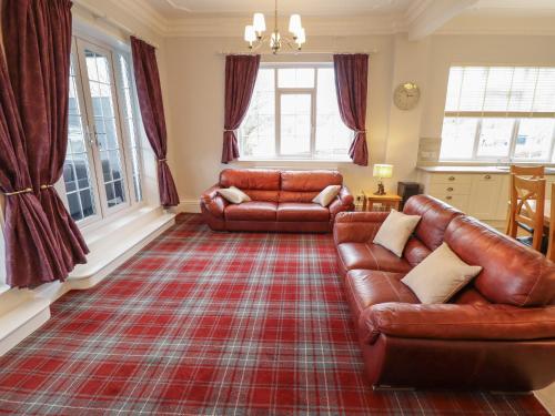 a living room with two leather couches and a rug at Castle Top Haven in Market Rasen