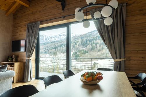 a dining room with a table and a large window at CASA IL TRAMONTO Val di Sole in Commezzadura