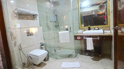 a bathroom with a shower and a toilet and a sink at SkyCity Hotel Gurgaon in Gurgaon