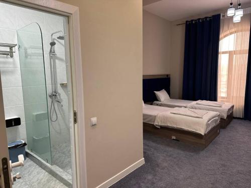 a bedroom with two beds and a glass shower at Silver Hotel in Samarkand