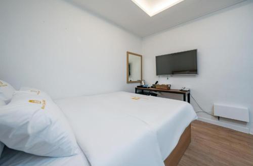 a white bedroom with a bed and a television at Must Stay Mokdong in Seoul