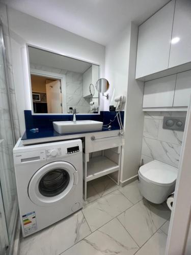 a bathroom with a washing machine and a sink at Batumi Orbi City in Batumi