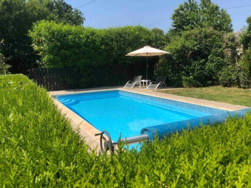 une piscine avec un parasol, une table et des chaises dans l'établissement Rose Cottage with seasonal Swimming Pool, à Le Mesnil-Gilbert
