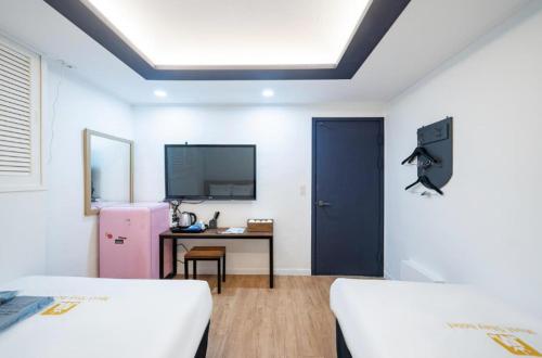 a room with two beds and a desk and a blue door at Must Stay Mokdong in Seoul
