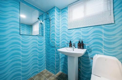 uma casa de banho em azulejos azuis com um lavatório e um WC em Must Stay Mokdong em Seul