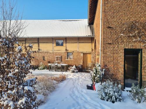 a brick building with a courtyard in the snow at Vakantiewoning in monumentale boerderij met yurt in Eckelrade