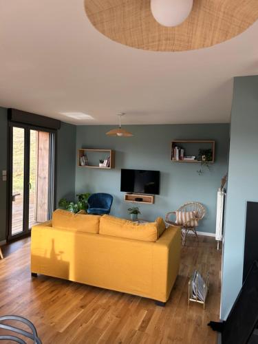 sala de estar con sofá amarillo y TV en Refuge au coeur des Vosges en Aumontzey