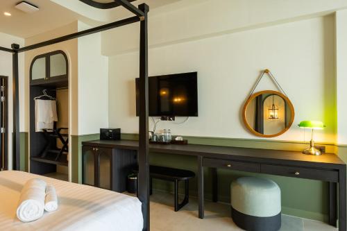 a bedroom with a bed and a desk with a mirror at Shamrock Chiangmai Hotel-Adult Only in Chiang Mai