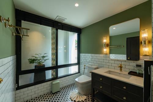 a bathroom with a toilet and a sink and a mirror at Shamrock Chiangmai Hotel-Adult Only in Chiang Mai