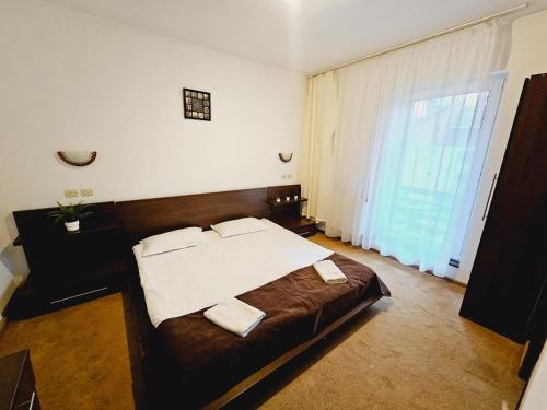 a bedroom with a large bed and a large window at VILA GALBENA - Poiana Brasov in Poiana Brasov