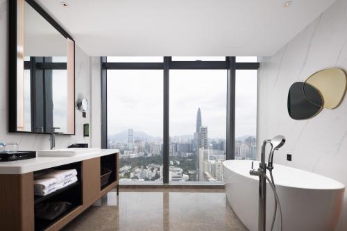 Hampton by Hilton Shenzhen Futian Huaqiangbei في شنجن: حمام مع حوض استحمام و نافذة كبيرة