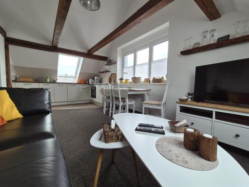 sala de estar con sofá, mesa y TV en gemütliche Ferienwohnung in Seenähe, en Neustrelitz
