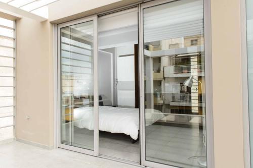 een slaapkamer met glazen schuifdeuren en een bed erin bij Bright Loft With Terrance - Next to Metro Kerameikos in Athene