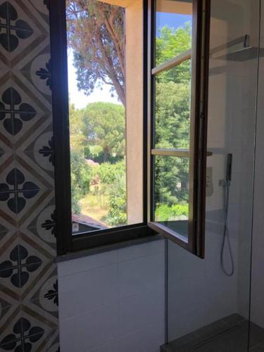 a window in a bathroom with a view of a tree at Locanda dei Sette Limoni - camere e residence in Vada