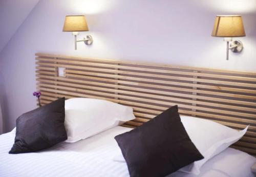 a bed with two black and white pillows on it at Logis Hôtel La ferme du Blanchot in Crossac
