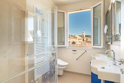 a bathroom with a toilet and a sink and a window at RivieraRent La Terrazza sul mare in Pietra Ligure