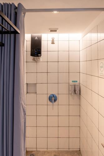 a bathroom with a white tiled wall with a shower at Bobopod Thamrin, Jakarta in Jakarta