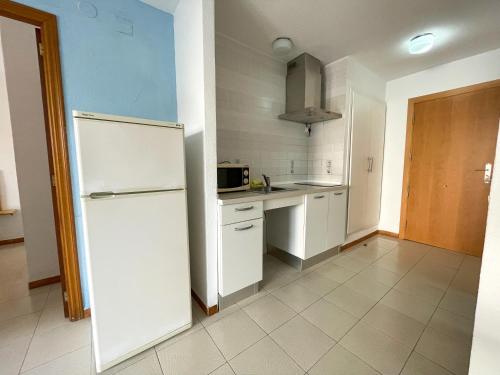 cocina con armarios blancos y nevera blanca en Apartamentos Bernat 3000, en Oropesa del Mar