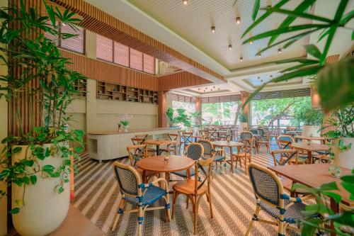a restaurant with wooden tables and chairs and plants at Mutiara Carita Cottages in Carita