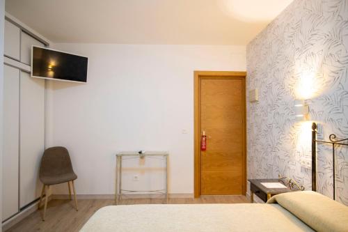 a bedroom with a bed and a television on a wall at Hotel Manzanito in Antequera
