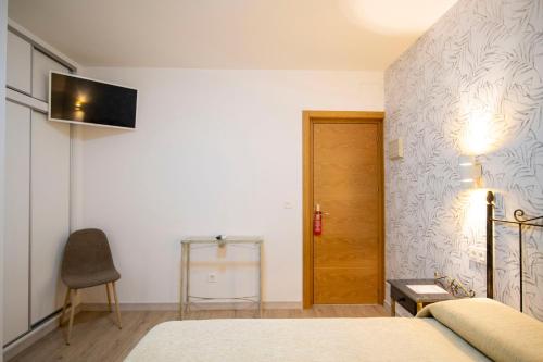 Un dormitorio con una cama y un televisor en una pared. en Hotel Manzanito, en Antequera