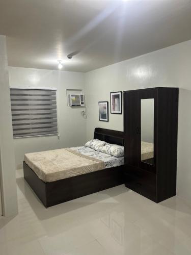 een slaapkamer met een groot bed en een spiegel bij BRIA FLATS LAS PINAS in Manilla
