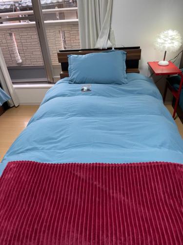 un letto blu con piumone rosso in una camera da letto di 孔雀民宿 ad Osaka