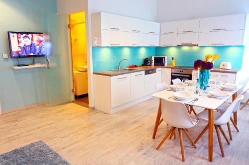 a kitchen with a table with white chairs and a tv at Central Stylish Apartments in Budapest