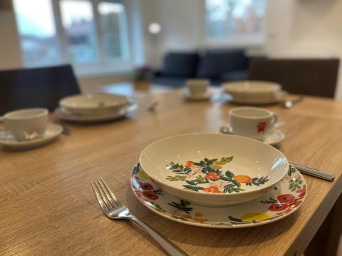 a table with a bowl and plates and a fork at Ferienwohnung Bergblick in Bayerisch Gmain