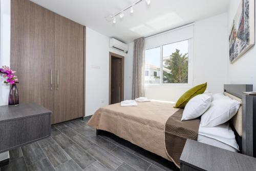 a bedroom with a large bed and a window at Green Bay Villa #15 in Protaras