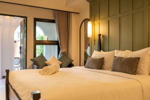a bedroom with a large white bed with a window at Shamrock Chiangmai Hotel in Chiang Mai