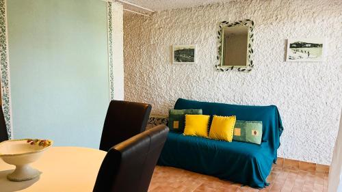 un salon avec un canapé bleu avec des coussins jaunes dans l'établissement Studio Cocody 5 Lumio, à Lumio