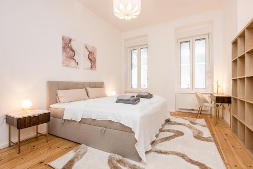 a white bedroom with a large bed and a desk at Schiller Apartment Neukölln in Berlin