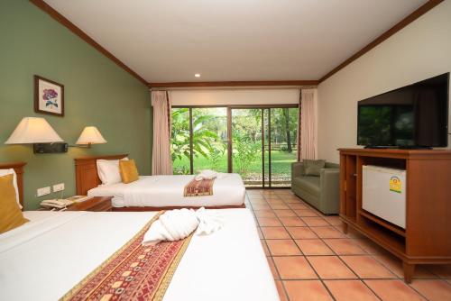a hotel room with two beds and a flat screen tv at Comsaed River Kwai Resort in Kanchanaburi