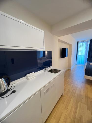 a white kitchen with a sink and a living room at Orbi City Batumi in Batumi