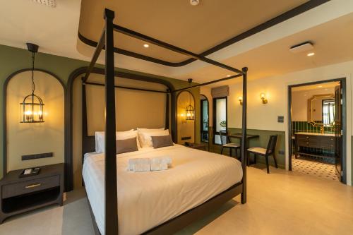 a bedroom with a canopy bed with a desk and a table at Shamrock Chiangmai Hotel-Adult Only in Chiang Mai