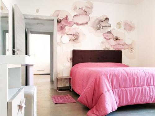 Un dormitorio con una cama rosa y una pared con nubes en Casa Contessa lago Maggiore, en Caravate