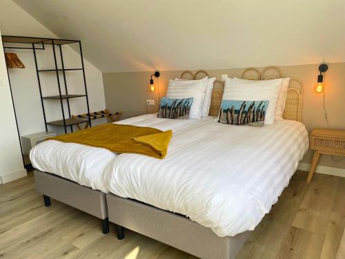 ein Schlafzimmer mit einem großen weißen Bett mit Kissen in der Unterkunft Bij het bos Texel in De Koog