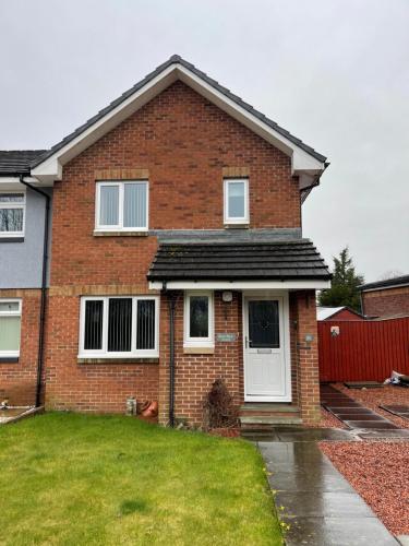 una casa de ladrillo rojo con puerta blanca en Kilmarnock, en Kilmarnock