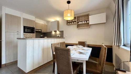 une cuisine et une salle à manger avec une table et des chaises blanches dans l'établissement Chez Nannou et Chris, à Fort-Mahon-Plage