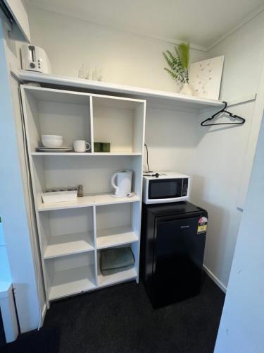 a small kitchen with a refrigerator and a microwave at Double Bedroom with Private Bathroom in Porirua