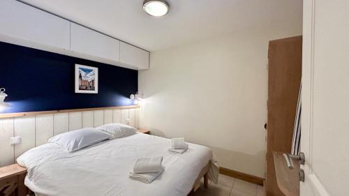 - une chambre avec un grand lit blanc et un mur bleu dans l'établissement Chez Nannou et Chris, à Fort-Mahon-Plage