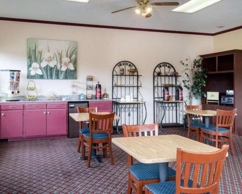 a restaurant with tables and chairs and pink cabinets at Rodeway Inn in Greenwood